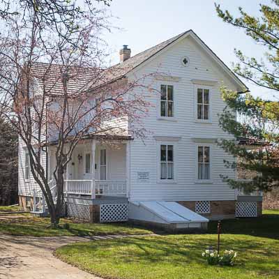 The Weidner Farmhouse, a two-story white 1850's farmhouse moved to the back corner of the Stempel parking lot and used as a museum by the Long Grove Historical Society